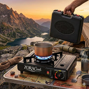 ZORACook Portable Gas Stove cooking outdoors on a rock ledge with its carry case